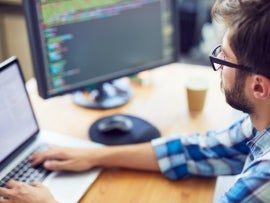 Close up shot of a young software developer working hard at his desk.